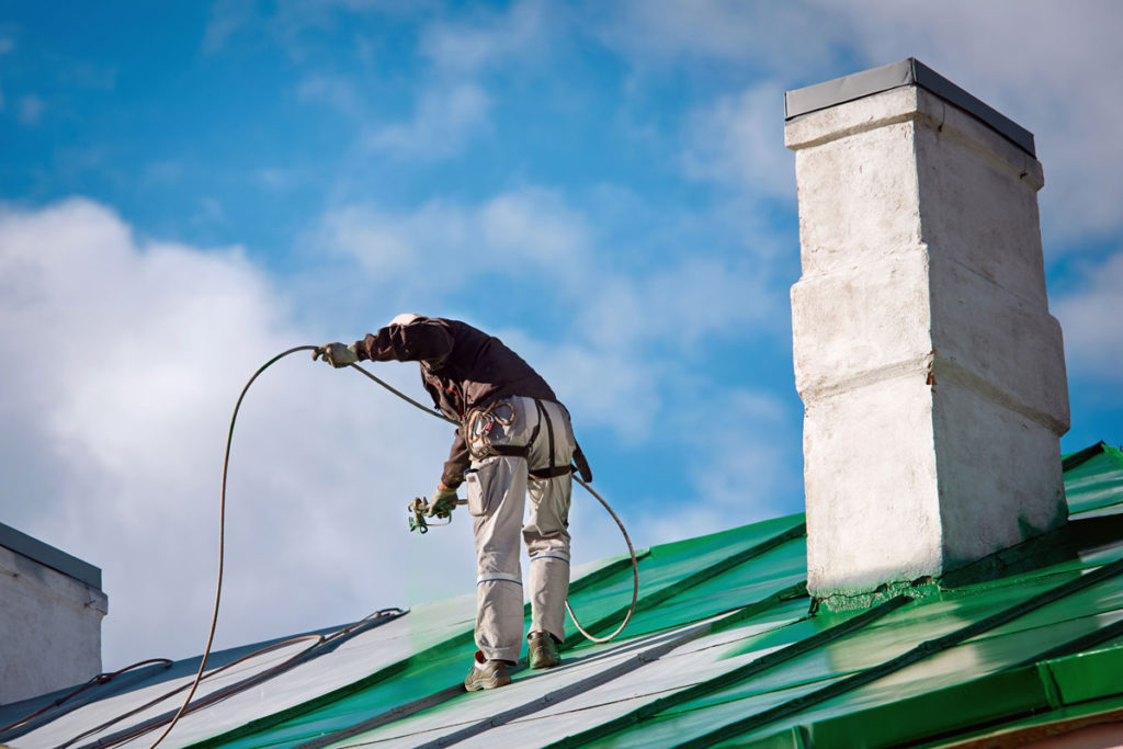 Team member painting roof green