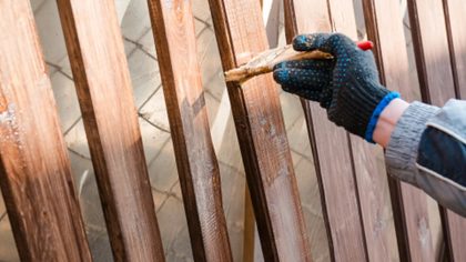 Fence Restoration - someone staining a wooden fence